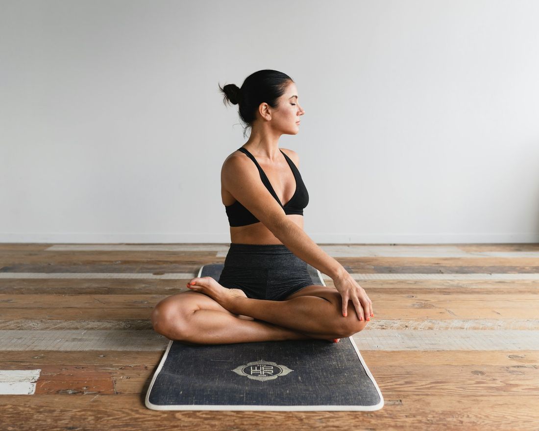Une élève assise sur son tapis, dans la lumière du studio