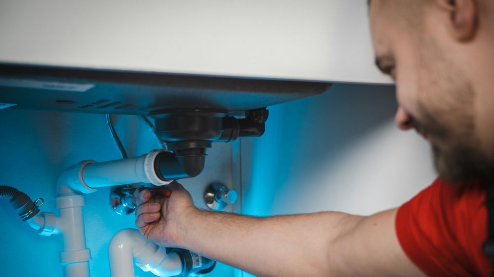 Plombier remplaçant le siphon sous un lavabo